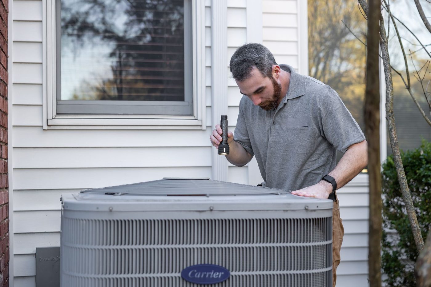 Service technician inspecting HVAC equipment outside a home
