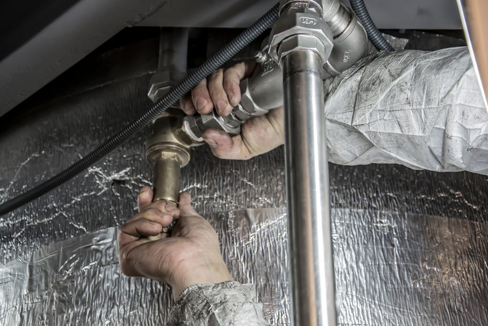 Plumber installing pipe fittings with hand tools