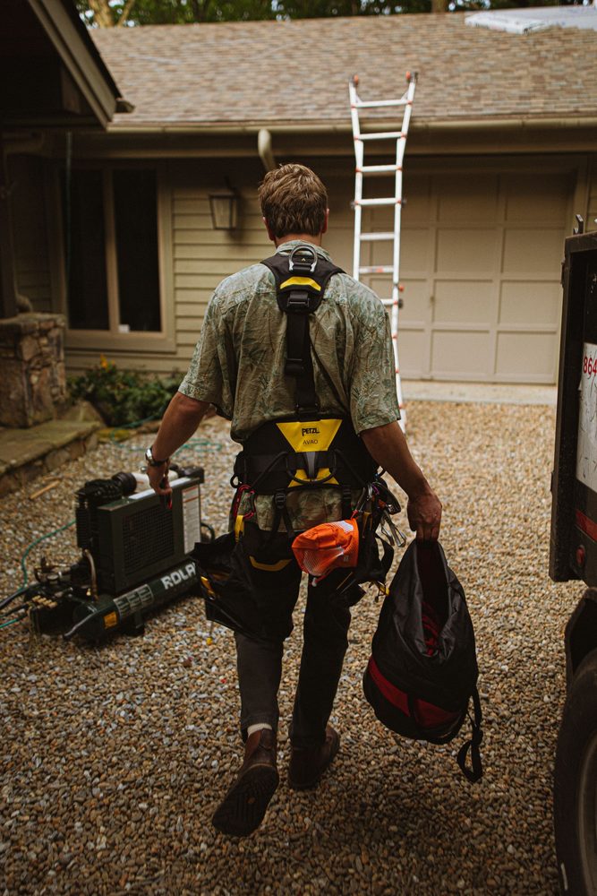 Roofer in safety gear approaching a residential roof project